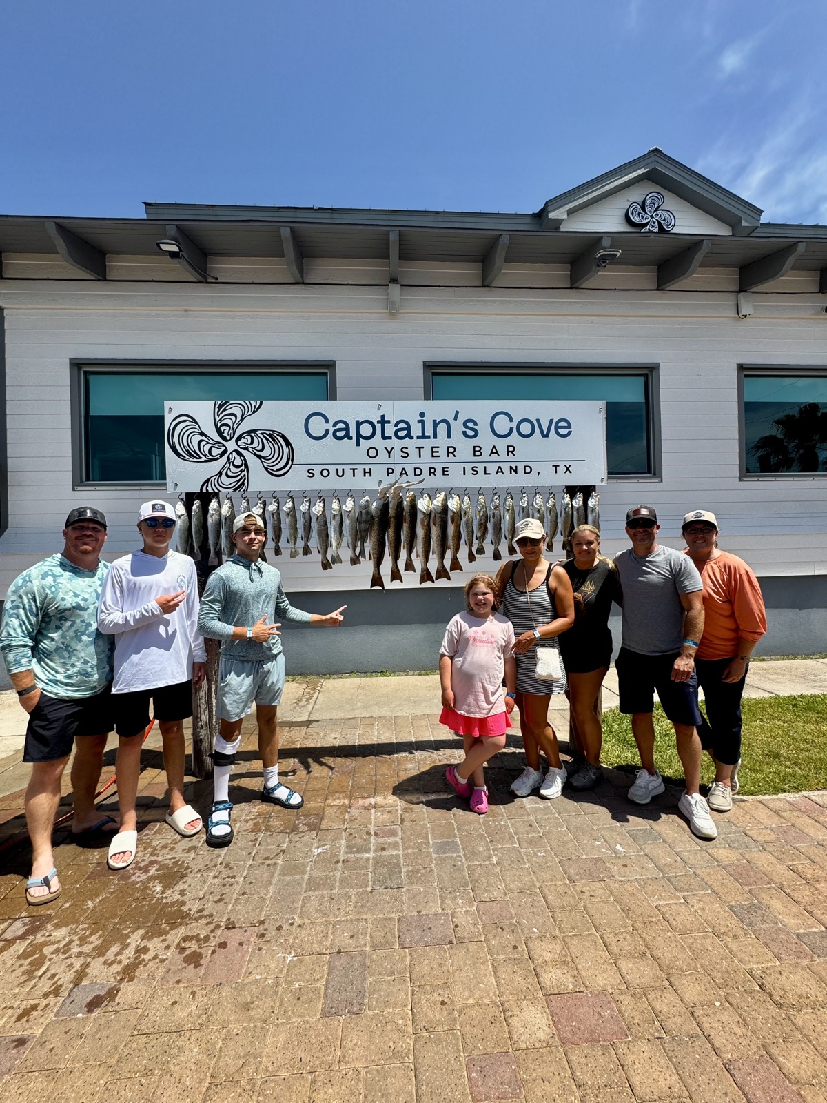 Family group with a full stringer of fish in front of Captain's Cove Oyster Bar, South Padre Island