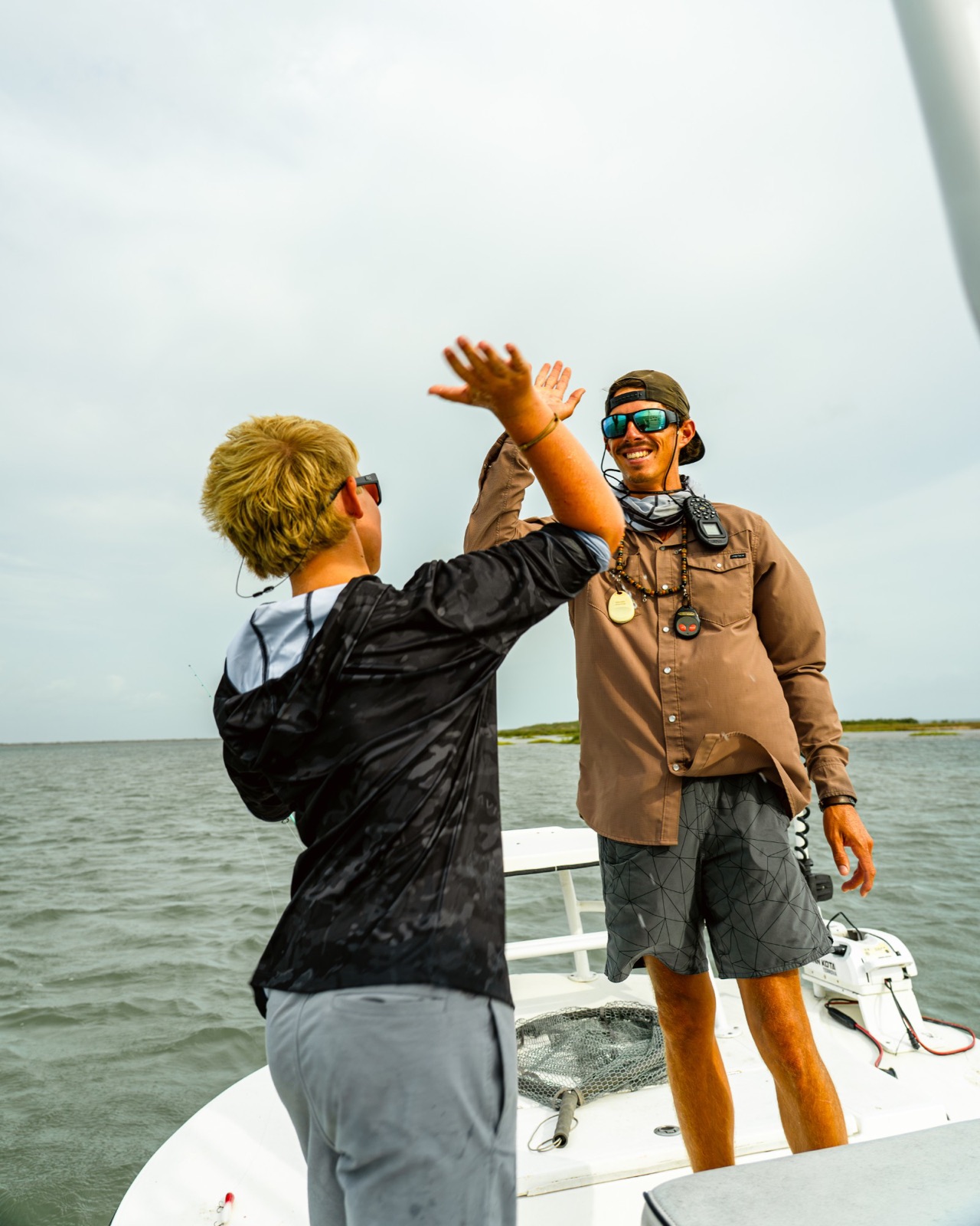 Capt. Trevor Kucia high-fiving a young angler on the bow