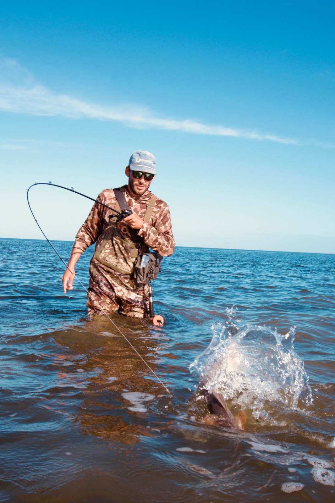 Wade fisherman fighting a redfish on the flats