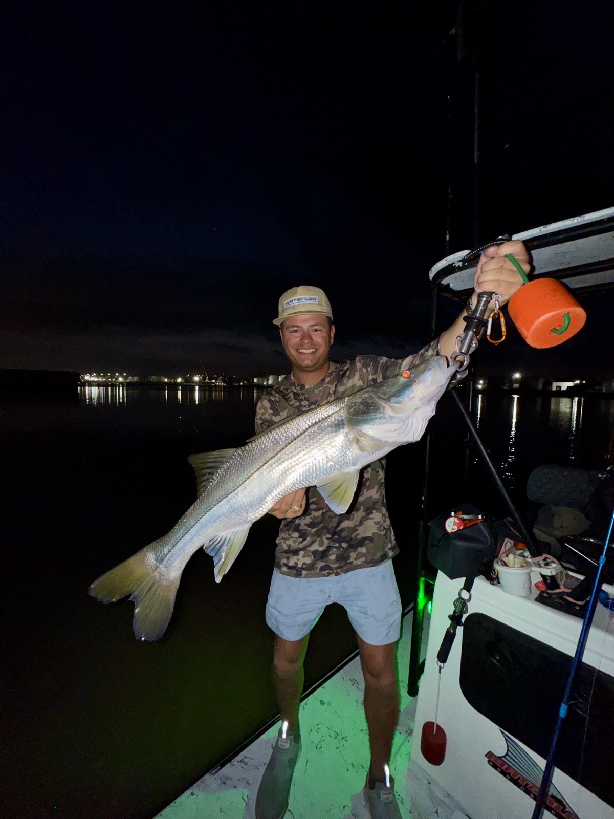 Angler holding a big snook on the boat at night