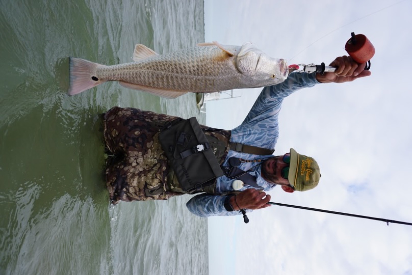 Angler in waders holding up a redfish