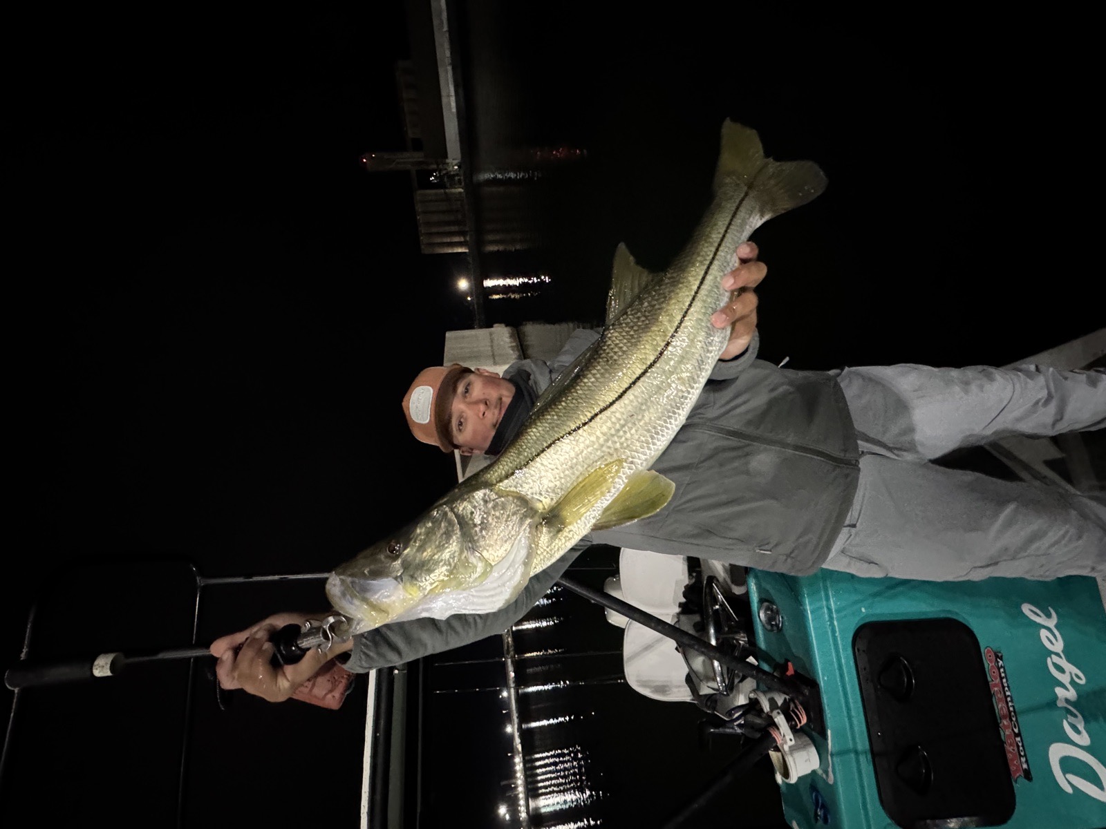 Angler with a snook on the boat at night