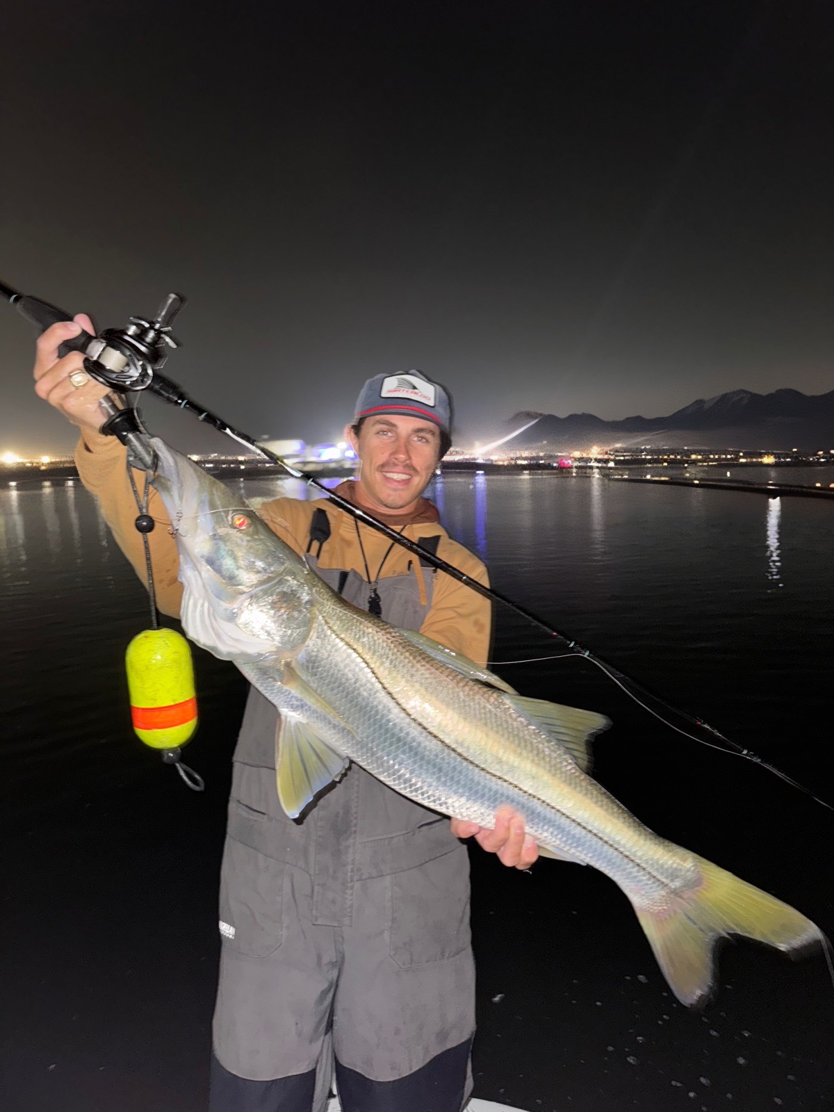 Angler holding a long snook at night