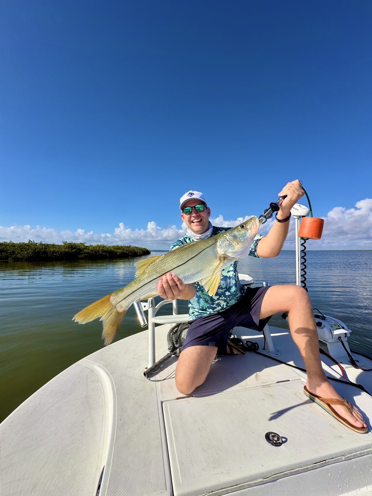 Angler kneeling on the bow with a big snook