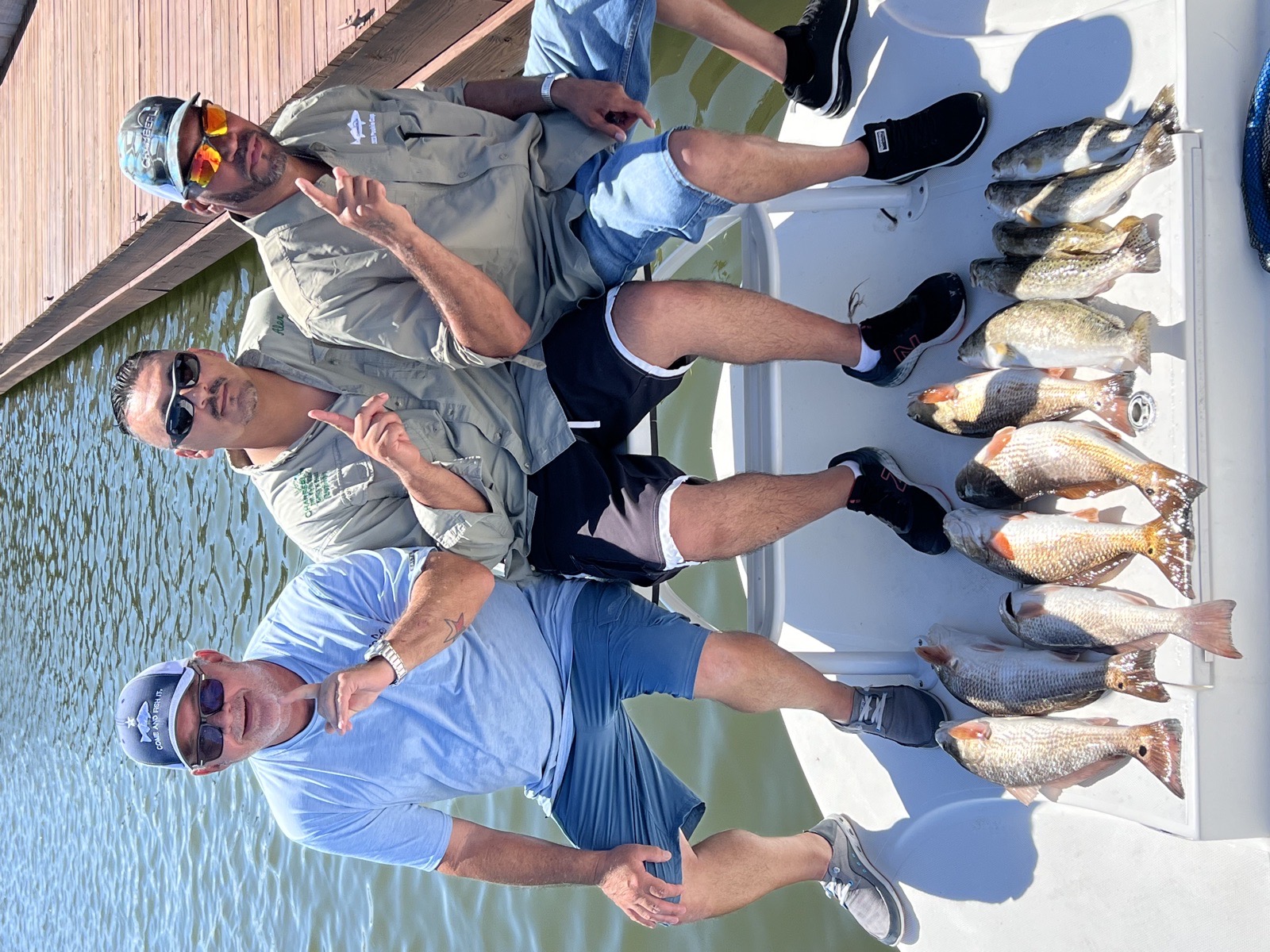 Three anglers on the boat with their catch of redfish and trout