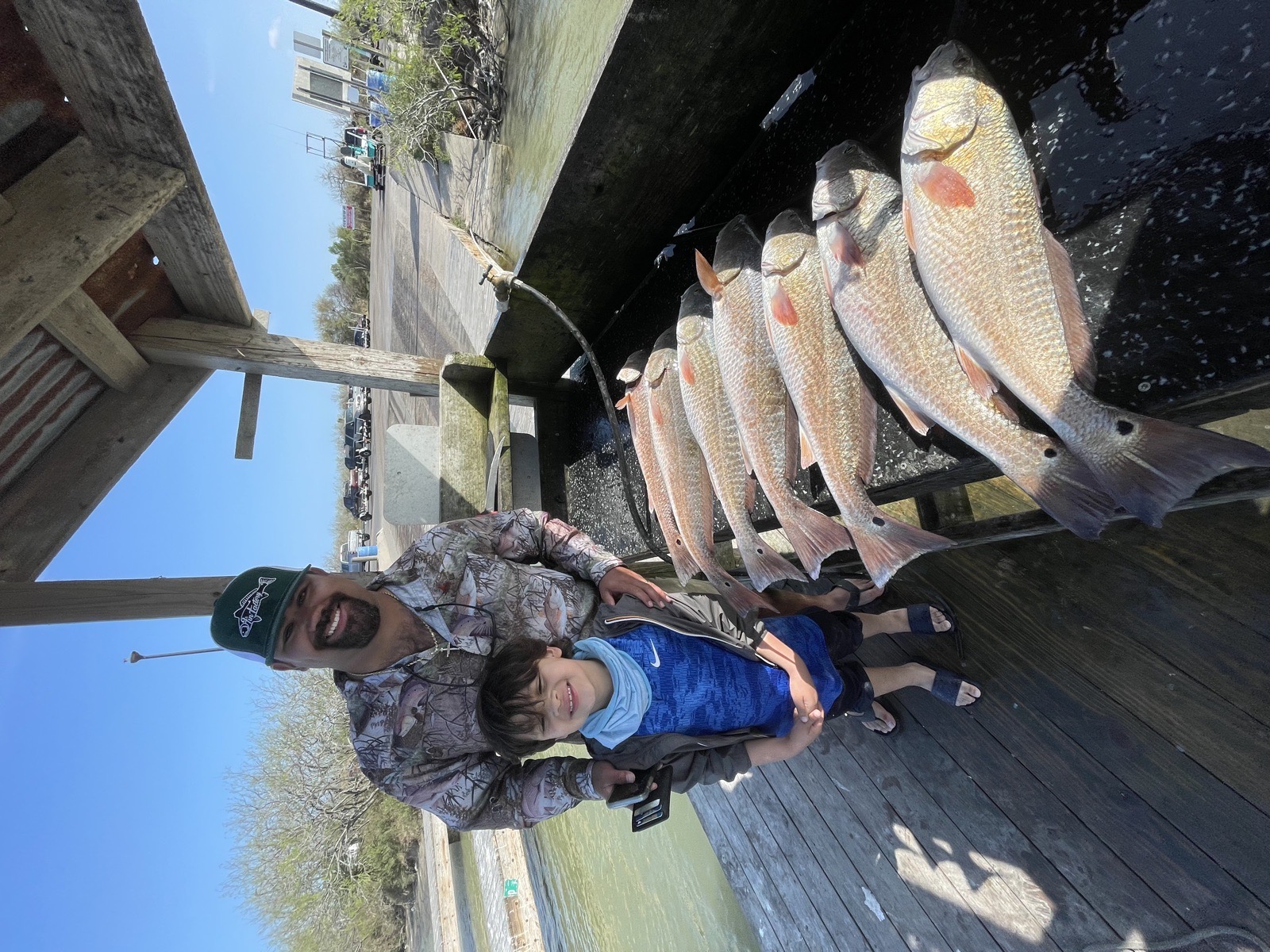 Father and young son with a catch of redfish on the dock