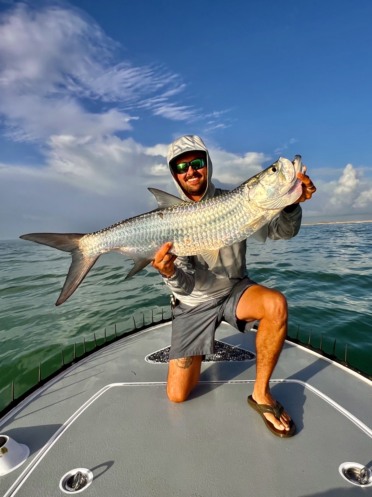 Capt. Trevor Kucia kneeling on the bow holding a tarpon